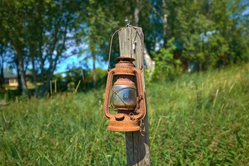 old gas kerosene lamp hanging on a wooden pole