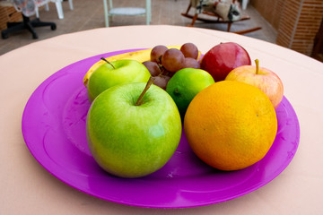 Apples, bananas, grapes, a lemon and an orange on the tray