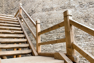 A wooden staircase with massive railings descends near the fortress wall. Historical background.