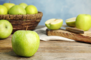 Fresh ripe green apple on wooden table against blue background, space for text