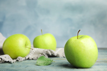 Fresh ripe green apples on wooden table against blue background, space for text