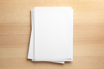 Stack of blank paper sheets for brochure on wooden background, top view. Mock up