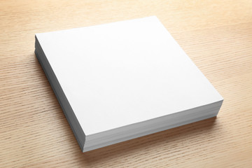 Stack of blank paper sheets for brochure on wooden background. Mock up