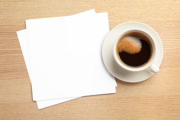 Blank paper sheets for brochure and cup of coffee on wooden background, flat lay. Mock up