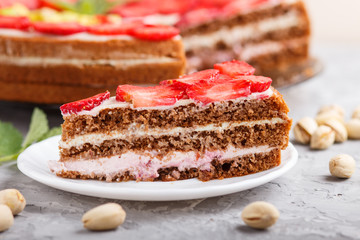 Homemade cake with yoghurt cream, strawberry and pistachio on a gray concrete  background. side view.