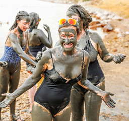 Women applying mud to themselves on the shore of the Dead Sea in Jordan as an ancient traditional spa treatment. 