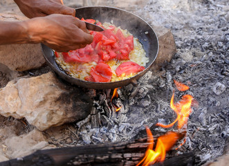 Cooking food, onions, tomatoes and bread, over and open fire. 