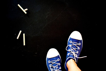top view of feet wearing blue dotted sneakers on black background with copy space