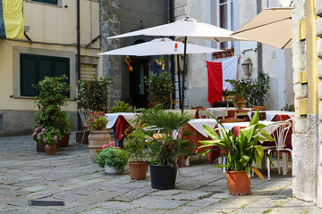 Street cafe or restaurant with decorated tables and flowerpots in the old town of Fivizzano, a small Lunigiana city in the province of Massa and Carrara, Tuscany, Italy