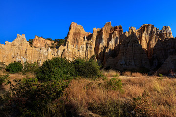 Fototapeta premium Earth Forest of Yuanmou in Yunnan Province, China - Exotic earth and sandstone formations glowing in the sunlight. Naturally formed pillars of rock and clay with unique erosion patterns. China Travel