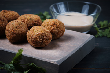 Classic hummus balls with thin sauce on a wooden board on a dark wooden background. National, vegetarian dish.