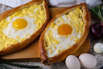 Two Adjar Khachapuri on a wooden board. Oven cake served for food. Georgian cuisine.