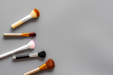 Brushes for make up on gray visagiste work desk background top view copyspace