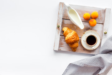 croissant, fruit and coffee with cream for homemade breakfast on the tray on white background top view space for text