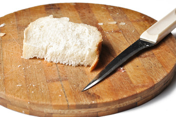 A piece of bread and a knife on a wooden board isolated on a white background.