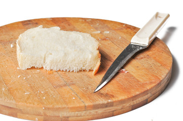 A piece of bread and a knife on a wooden board isolated on a white background.