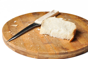 A piece of bread and a knife on a wooden board isolated on a white background.
