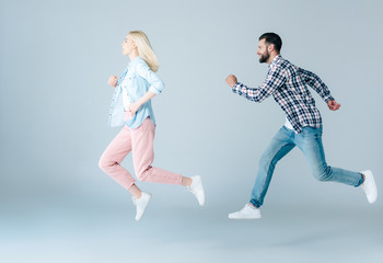 side view of man and girl in casual clothes jumping on grey
