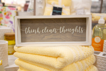 Cute sign with the text "think clean thoughts" on top of a set of yellow towels inside of a home décor store.