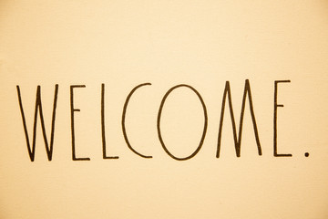 Sepia toned Welcome sign in simple handwritten serif font.