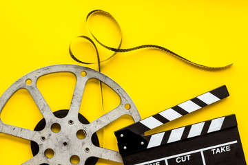 Watch film in cinema with video tape and clapperboard on yellow background top view