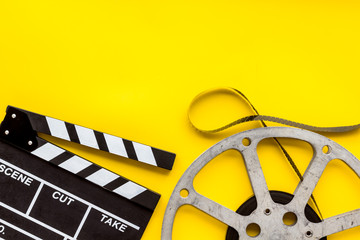Watch film in cinema with video tape and clapperboard on yellow background top view