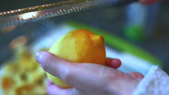 Female home cook zesting a freshly picked organic lemon in the kitchen.