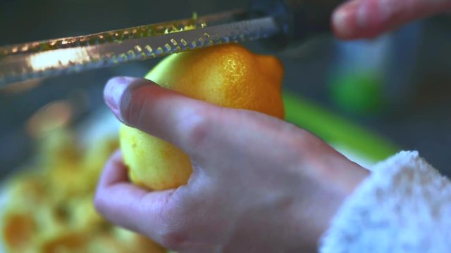 Female home cook zesting a freshly picked organic lemon in the kitchen.