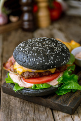 Black Burger with meat, cheese and bacon on wooden board