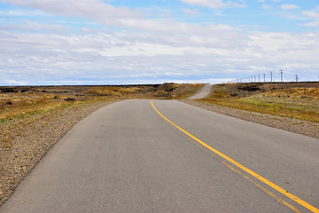 Fototapeta na wymiar Curva en bajada de ruta de asfalto con cielo azul y nubes de fondo