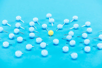 yellow paper clip rounded by blue paper clips on blue background, violence concept