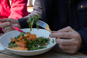 Group of family and friends share foods and having lunch time outdoor together on wooden table in sunny day