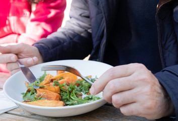 Group of family and friends share foods and having lunch time outdoor together on wooden table in sunny day