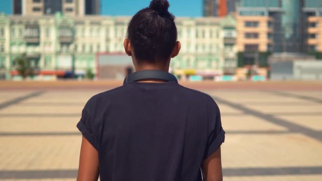 back view young man with headphones walking in urban city turn to the camera happy smiling