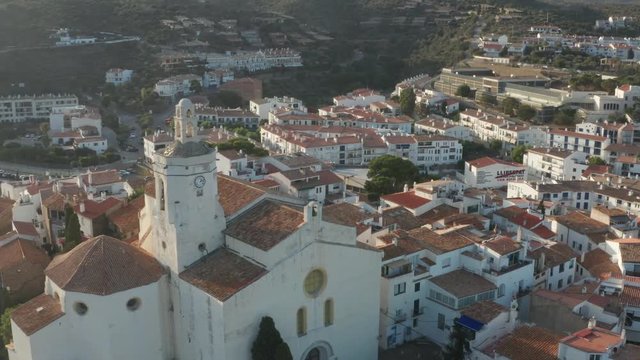 Aerial view of historic building of St. Mary's church in Cadaques illuminated with sunlight. Drone shot of beautiful sunlit cityscape, old houses of medieval town
