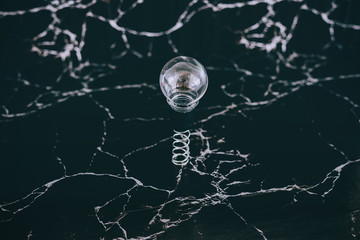 idea lightbulb popping up on spring with black marble background