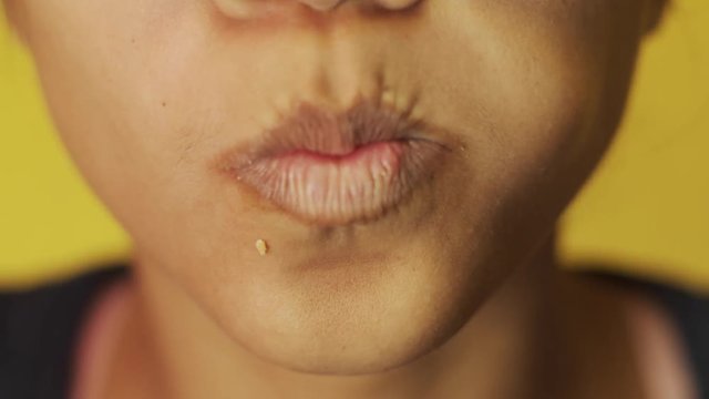 Closeup of a woman's mouth eating a hamburger at a fast food restaurant.