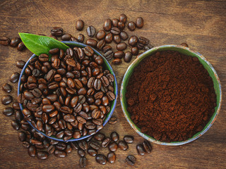 Coffee beans and ground powder on wooden background.
