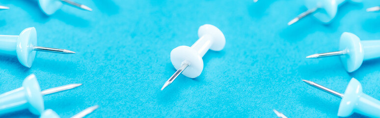 panoramic shot of white paper clip in middle of blue paper clips on blue background, violence concept