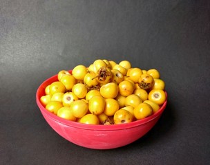 Yellow nances in red bowl with black background