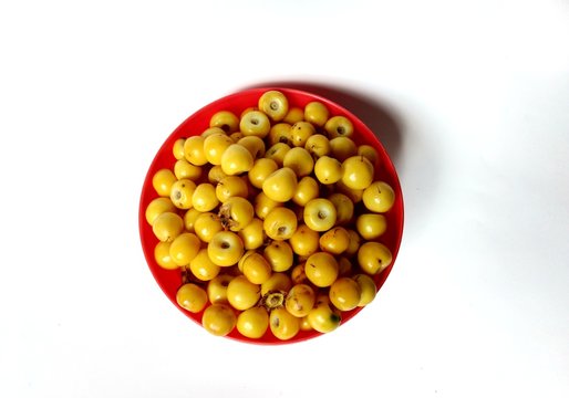 Yellow nanches fruit in red bowl with white background
