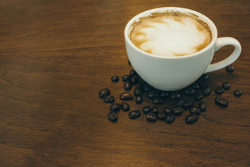 Coffee cup and coffee beans on wooden table  in cafe