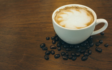 Coffee cup and coffee beans on wooden table  in cafe
