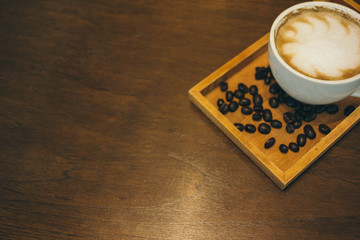 Coffee cup and coffee beans on wooden table  in cafe