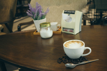 Coffee cup and coffee beans on wooden table  in cafe