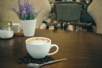 Coffee cup and coffee beans on wooden table  in cafe