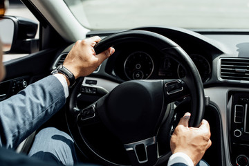 partial view of african american businessman in suit driving car
