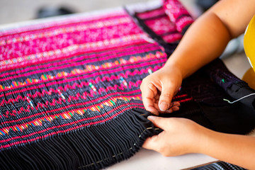 Close up hands using needle sewing Hmong skirt