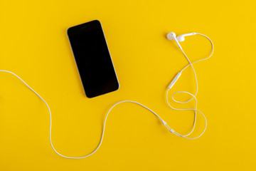 Obraz premium flat lay of modern music player device and earphones, minimalistic concept on color surface