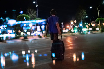 young traveler going to the journey vacation with wheeled baggage at night